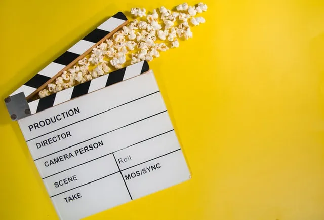 Clapper board with popcorn coming out of it and yellow background