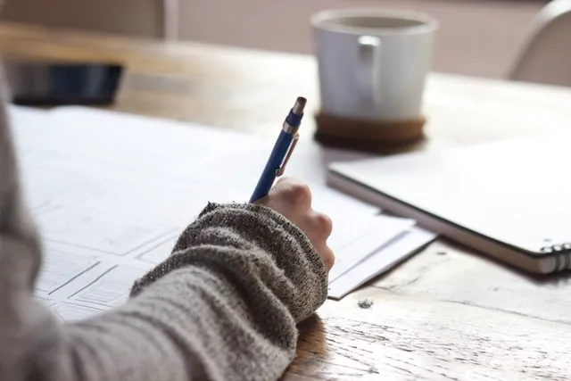 person writing on paper with pen